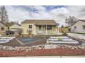 Charming, yellow single-story home featuring a landscaped front yard and a welcoming, covered porch at 1254 S Osceola St, Denver, CO 80219