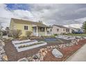 Quaint, yellow home with a landscaped front yard, raised garden beds, rock accents, and a covered porch at 1254 S Osceola St, Denver, CO 80219