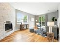 Bright living room with a stone fireplace, hardwood floors, large windows, and sliding glass doors to the backyard at 2077 S Clayton St, Denver, CO 80210