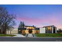 Modern home exterior featuring stone accents, expansive windows, and professional landscaping at dusk at 2960 E Floyd Dr, Denver, CO 80210