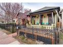 Charming home with covered porch, black wrought iron fence, and colorful landscaping highlighting neighborhood charm at 3313 Curtis St, Denver, CO 80205