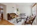 Cozy living room featuring a vintage piano, comfortable seating, and bright natural light at 3575 W Hamilton Pl, Denver, CO 80236