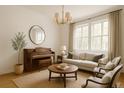 Bright living room with neutral tones, a piano, and natural light streaming through large windows at 3575 W Hamilton Pl, Denver, CO 80236