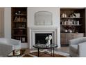 Cozy living room featuring a fireplace with decorative mantle, built-in shelving, and stylish furniture around a glass-topped table at 4131 Quivas St, Denver, CO 80211