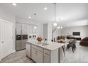 Modern kitchen featuring stainless steel appliances, a granite-topped island and open sightlines to living and dining spaces at 18399 Field Mint Pt, Parker, CO 80134