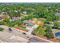 Aerial view of a gray home with a driveway, a tennis court, a pool, and mature trees in the neighborhood at 10197 E Mississippi Ave, Aurora, CO 80247