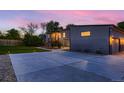 Exterior view of home showcasing the entryway, a wide driveway, and tasteful landscaping at dusk at 10197 E Mississippi Ave, Aurora, CO 80247