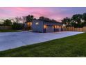 Spacious three-car garage with a wide driveway and manicured lawn at dusk at 10197 E Mississippi Ave, Aurora, CO 80247