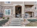 Exterior of building with stone accents, stairs, and well-maintained landscaping at 9568 W San Juan Cir # 203, Littleton, CO 80128