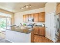 Well-lit kitchen featuring wood cabinets, a center island with sink, and stainless steel appliances at 1404 Tonkin Pl, Longmont, CO 80504