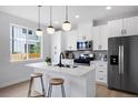 Modern kitchen with white cabinets, stainless steel appliances, an island with seating and pendant lighting at 4020 Upham St, Wheat Ridge, CO 80033