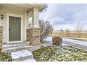 Close-up of a covered front porch entry, featuring brick columns and professionally maintained landscaping at 13001 Grant Cir # C, Thornton, CO 80241