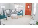 Inviting living room with grey sofa, blue accent chairs, and natural light streaming through the front window at 7751 S Curtice Dr # E, Littleton, CO 80120
