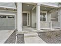 Close-up view of the covered front porch with white columns and a dark wood front door at 946 Compass Dr, Erie, CO 80516