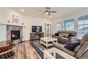 Bright living room featuring a cozy fireplace, ceiling fan, and comfortable seating area with hardwood floors at 946 Compass Dr, Erie, CO 80516