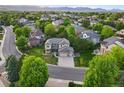 Expansive aerial view of a home nestled among mature trees with mountain views in the distance at 5683 Fig Way, Arvada, CO 80002