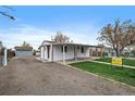 Side view of the home showcasing the gravel driveway and covered porch at 7460 Krameria Dr, Commerce City, CO 80022