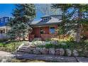 Quaint brick home with stone landscaping, a cozy porch, and mature trees in a peaceful setting at 1716 S Ogden St, Denver, CO 80210