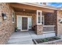 Inviting front porch showcasing stone accents, a cozy seating area, and a stylish front door at 26741 E Arbor Dr, Aurora, CO 80016