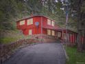 Charming red home with stone foundation and covered parking in a serene wooded setting at 6837 S Brook Forest Rd, Evergreen, CO 80439