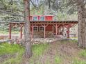 Charming red home with covered outdoor living space perfect for relaxation and entertaining at 6837 S Brook Forest Rd, Evergreen, CO 80439