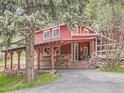 Charming red home with covered outdoor living space perfect for relaxation and entertaining at 6837 S Brook Forest Rd, Evergreen, CO 80439