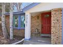 Close up of front entry with brick facade, painted house number, and a bright red front door at 7761 Everett Way, Arvada, CO 80005