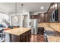 Bright, open kitchen with stainless appliances, granite countertops, dark wood cabinets, and a large island at 9570 Kendrick Way, Arvada, CO 80007