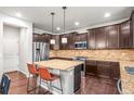 Stylish kitchen with dark wood cabinets, granite countertops, stainless appliances, and a center island with seating at 9570 Kendrick Way, Arvada, CO 80007