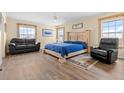 Bright main bedroom features a wooden bed frame, new wood-look flooring and large windows allowing natural light at 13640 County Road 182, Bennett, CO 80102