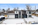 Stunning contemporary home with a combination of stone and white siding, modern windows, and a snow-covered front yard at 5258 Lions Paw St, Castle Rock, CO 80104