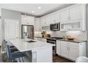 Modern kitchen featuring white cabinets, stainless steel appliances, island seating, and stylish backsplash at 8846 Yates Dr, Westminster, CO 80031