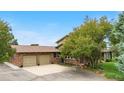 Spacious home with a two-car garage and a wide driveway, surrounded by green lawns and mature trees at 7583 W Trail South Dr, Littleton, CO 80125