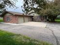 Charming brick home featuring an attached two-car garage and a large driveway at 7583 W Trail South Dr, Littleton, CO 80125