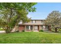 Charming two-story home featuring brick accents, complemented by a well-manicured lawn and mature trees at 7583 W Trail South Dr, Littleton, CO 80125