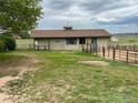Tan outbuilding or barn with fenced paddock and a weather vane on the roof at 7583 W Trail South Dr, Littleton, CO 80125