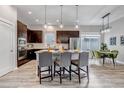 Modern kitchen with a central island, stylish pendant lighting, dark wood cabinetry, and stainless steel appliances at 6715 Raritan Dr, Denver, CO 80221