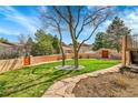 Picturesque backyard featuring lush green grass, a stone pathway, mature trees, and a stucco wall surround at 6201 Rain Dance Trl, Littleton, CO 80125