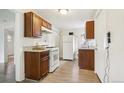 Functional kitchen featuring wooden cabinets, white appliances, and light granite countertops at 1340 Iola St, Aurora, CO 80010