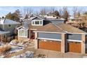 Two-story home with brick and siding, featuring a wood-toned garage door and landscaping at 17773 E Powers Dr, Centennial, CO 80015