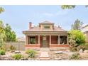 Inviting brick home featuring a covered front porch and mature landscaping at 2845 Quitman St, Denver, CO 80212