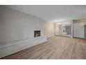 A spacious living room featuring a white brick fireplace, wood floors, and a mirrored wall at 4110 Hale Pkwy # 1E, Denver, CO 80220