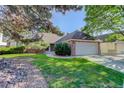 Charming brick home with a well-manicured lawn and a two-car garage, framed by mature trees at 6055 W Warren, Lakewood, CO 80227
