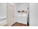 Functional laundry area equipped with a white washer and dryer, shelving, and an ironing board for convenience at 11865 Barrentine Loop, Parker, CO 80138