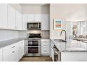 Well-lit kitchen featuring white cabinets, stainless steel appliances, and granite countertops at 14833 E Crestridge Dr, Centennial, CO 80015