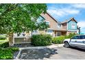 Townhouse exterior with lush landscaping, stone accents, and a parking area shaded by a large tree at 13271 Holly St # B, Thornton, CO 80241