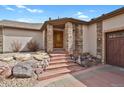 Inviting front entrance with stone pillars, terraced landscaping, and decorative wood door at 5265 Club Ct, Larkspur, CO 80118