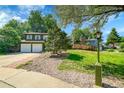 Charming two-story home with a two car garage, well-manicured lawn, mature trees and a green front lamp post at 2211 Sherman St, Longmont, CO 80501