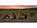 Beautiful stone home with a circular driveway situated on a spacious lot at sunset at 15958 Shadow Mountain Ranch Rd, Larkspur, CO 80118