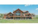Expansive back exterior featuring a stone facade, large windows, and covered balconies at 15958 Shadow Mountain Ranch Rd, Larkspur, CO 80118